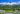 Green FlixBus travelling past forested mountains.
